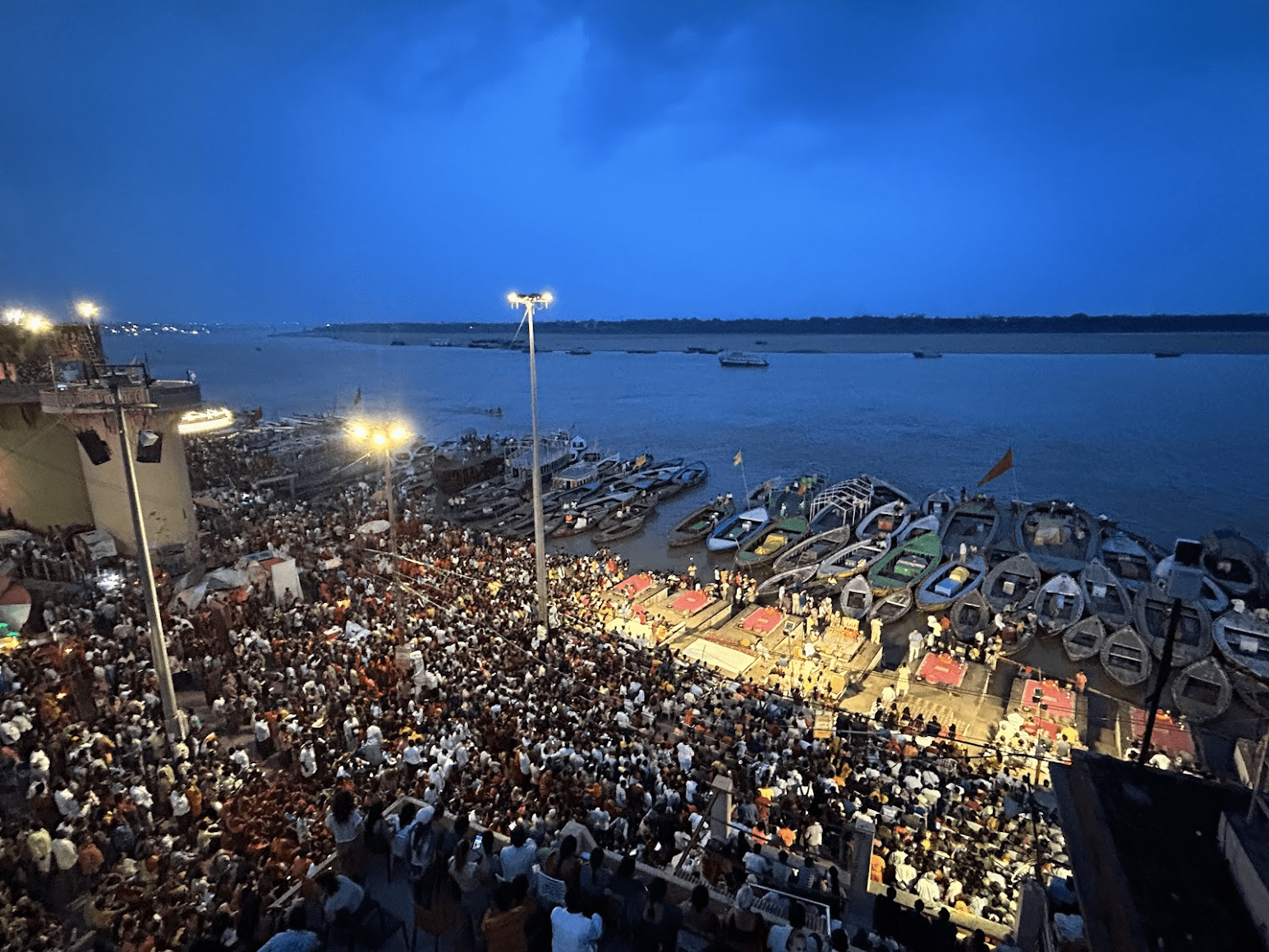 A wide shot of the Dhashashwamedh Ghat in Varanasi during a crowded evening ceremony.